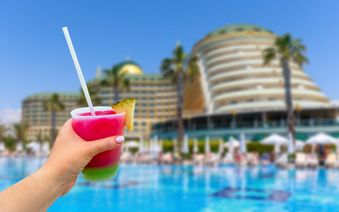 Zdjęcie przedstawia rękę kobiety trzymającą drinka podczas urlopu w luksusowym hotelu w Turcji