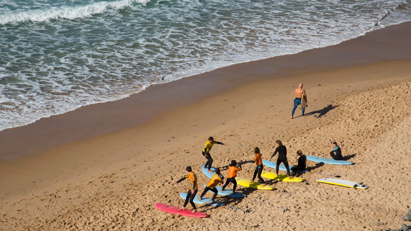 Na plaży ludzie uczący się surfować, w tle ocean