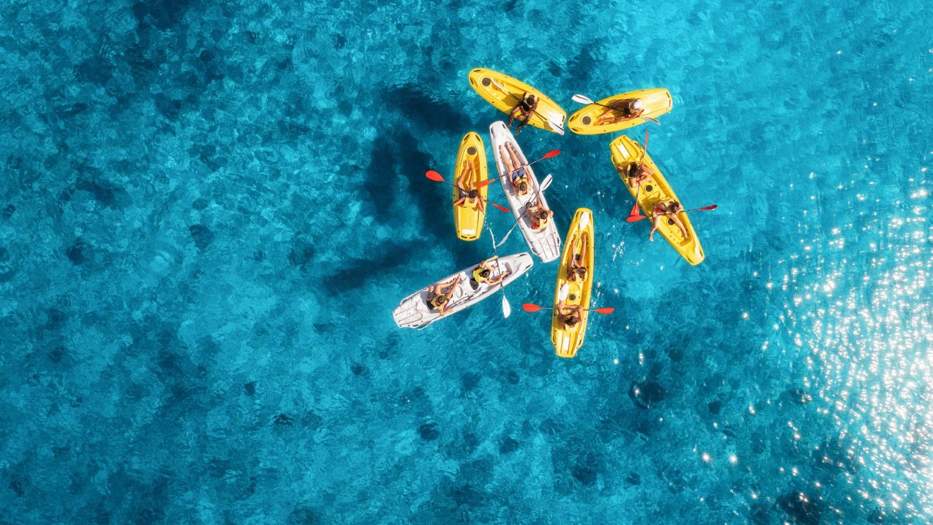 Aerial,View,Of,Yellow,Kayaks,In,Blue,Sea,At,Sunset