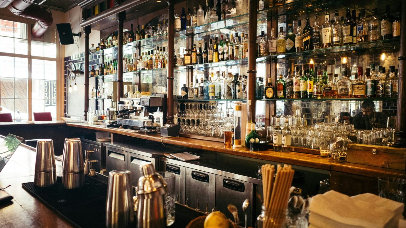 Zdjęcie przedstawia półkę z alkoholem w barze